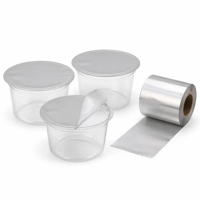 Clear cups sealed with silver lidding film, one partly peeled, beside a roll of the film